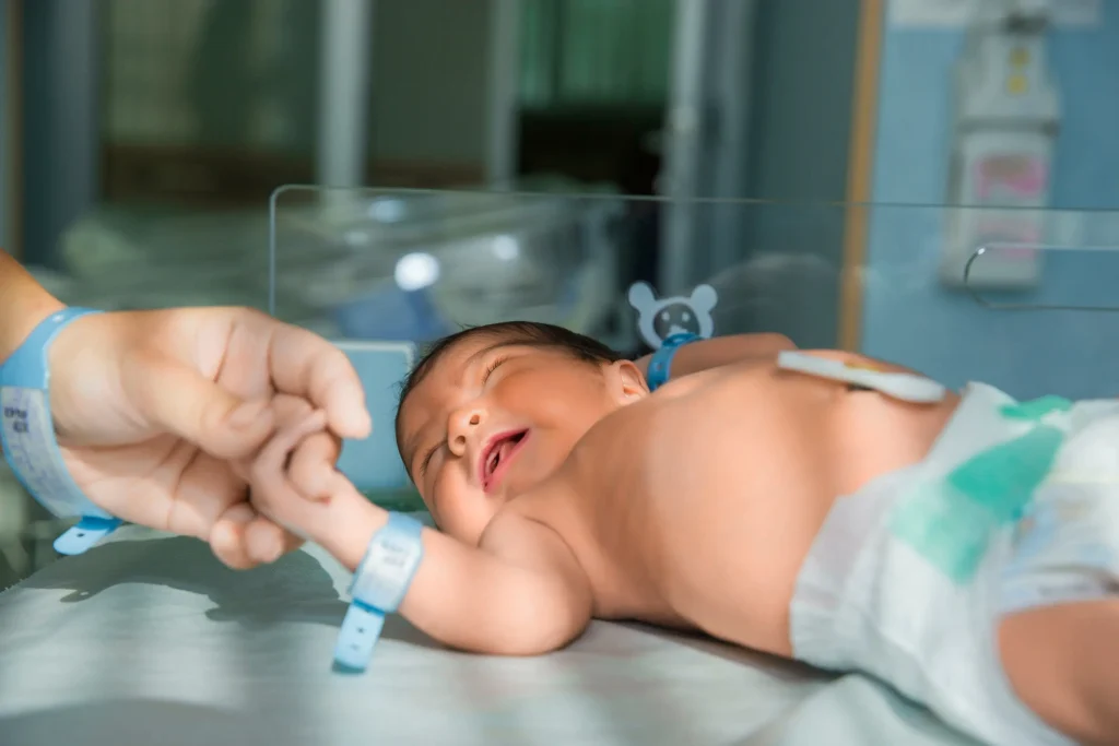 A baby is getting hand touch of an NICU nurse