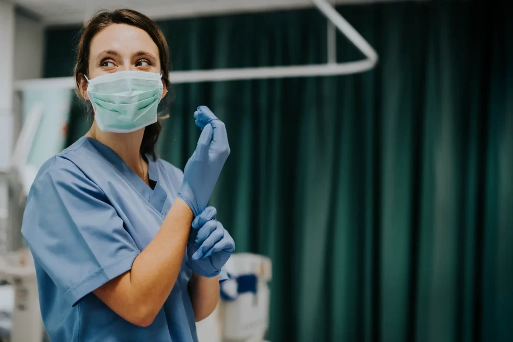 A registered nurse is wearing gloves in a hospital